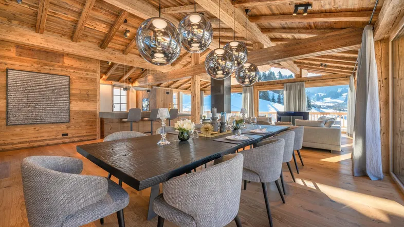 Eleganter Essbereich mit großem Holztisch, modernen Pendelleuchten und Zugang zum Wohnzimmer.