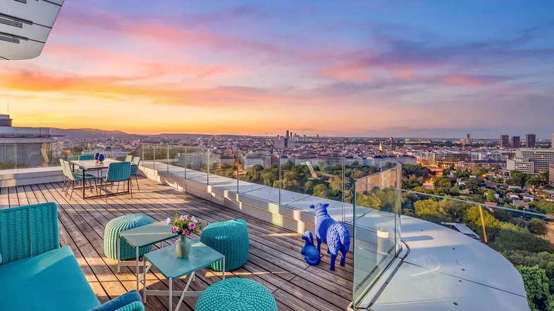 Große Dachterrasse mit modernen Outdoor-Möbeln und atemberaubendem Stadtblick bei Sonnenuntergang.
