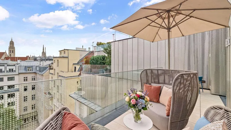 Große Dachterrasse mit bequemen Loungemöbeln, Sonnenschirm und weitem Blick über die Stadt.