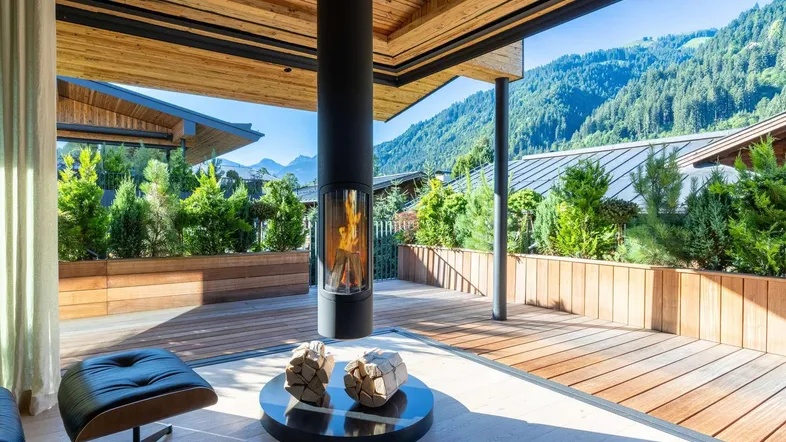 Überdachte Terrasse mit modernem Kamin, Holzdeck und atemberaubendem Bergblick.