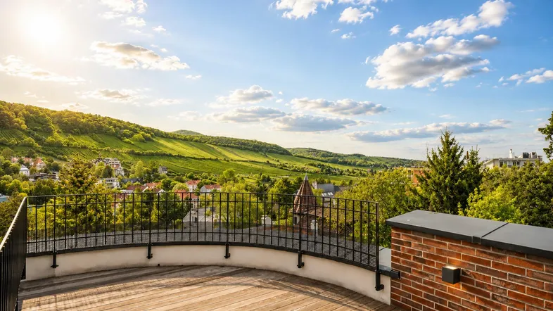 Große Holzterrasse mit Panoramablick auf die umliegende Landschaft und Weinberge unter blauem Himmel.