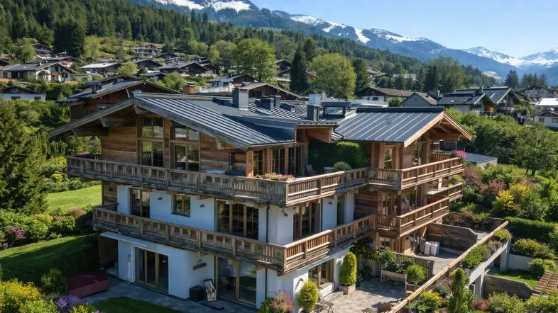 Großes Chalet mit mehreren Balkonen und Terrassen, umgeben von einem gepflegten Garten und mit Bergblick.