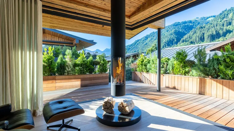 Offener Wohnbereich mit modernem Kamin, Holzboden und weitem Bergblick durch große Fenster.