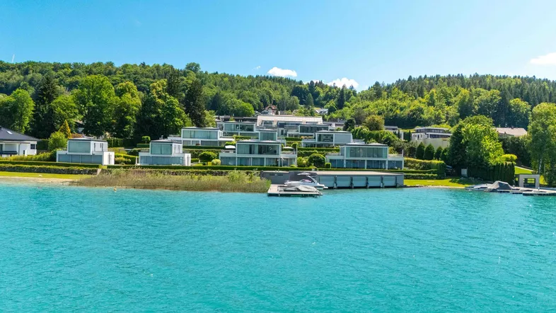 Moderne Villenanlage am Seeufer mit gestufter Architektur und weitem Blick auf das türkisfarbene Wasser.