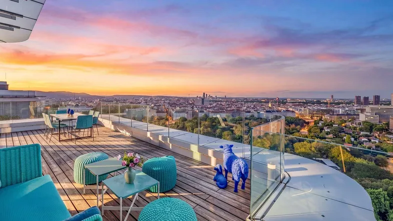 Große Dachterrasse mit modernen Outdoor-Möbeln und spektakulärem Stadtblick bei Sonnenuntergang.