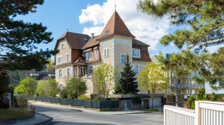 Elegantes historisches Gebäude mit markantem Turm und gepflegter Fassade an einer ruhigen Straße.
