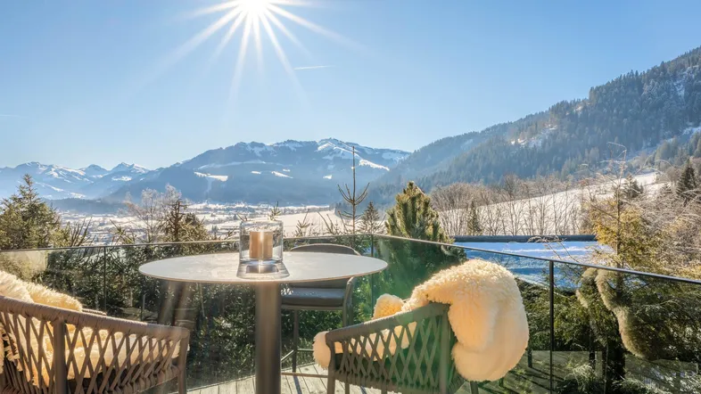 Gemütlicher Balkon mit Sitzgelegenheiten und weitem Blick auf die verschneite Berglandschaft.