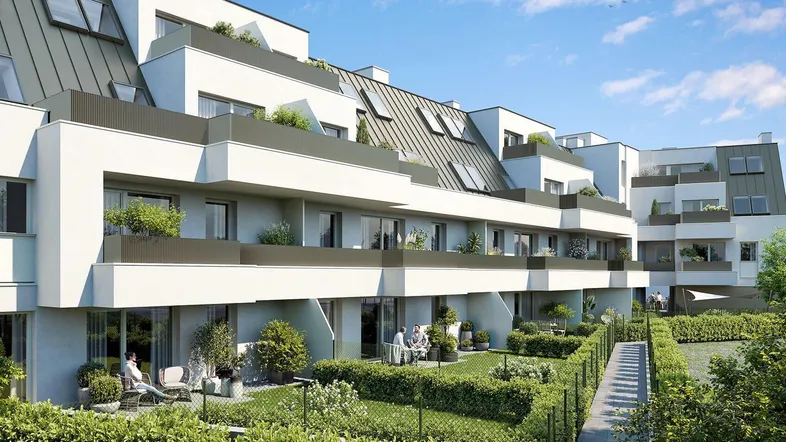 Moderne Wohnanlage mit mehreren Balkonen, Terrassen und begrünten Außenbereichen unter blauem Himmel.