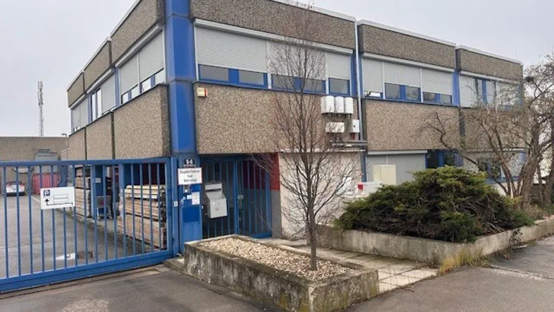 Gebäudeansicht eines Gewerbeobjekts mit blauen Akzenten und Rollläden an den Fenstern.