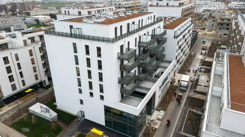 Luftaufnahme eines modernen Wohnkomplexes mit mehreren Gebäuden und Baustellen in der Umgebung.