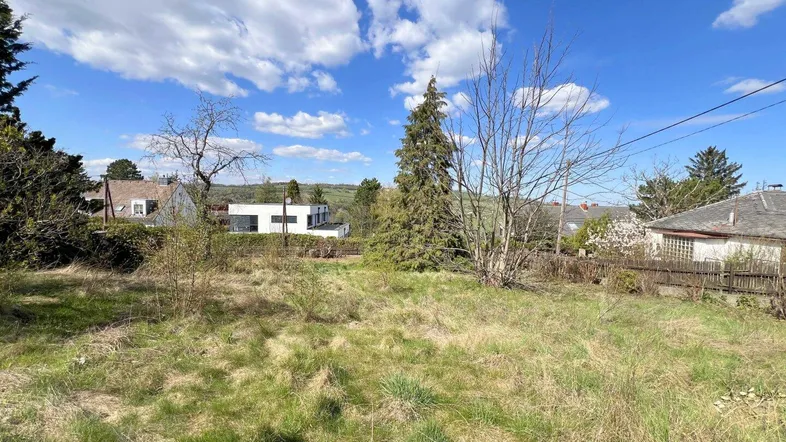 Ungenutztes Grundstück mit Grasbewuchs und Blick auf umliegende Häuser und Landschaft.