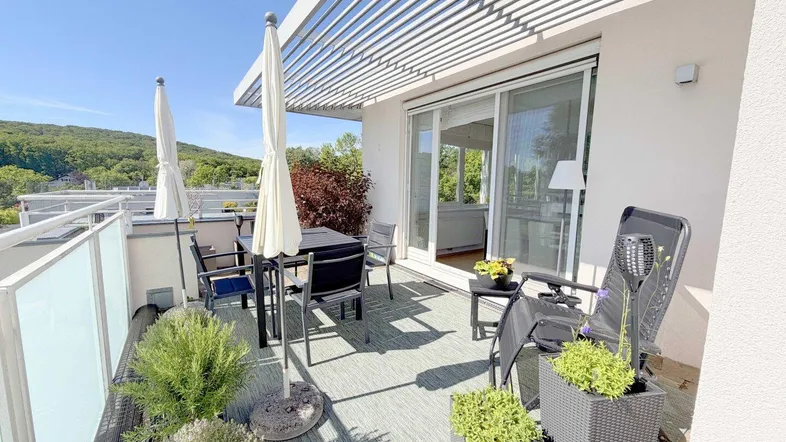 Geräumiger Balkon mit modernen Gartenmöbeln, Sonnenschirmen und Blick ins Grüne.