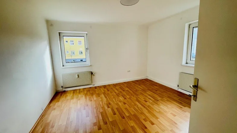 Helles Zimmer mit Parkettboden und zwei Fenstern, ideal als Schlaf- oder Arbeitszimmer nutzbar.