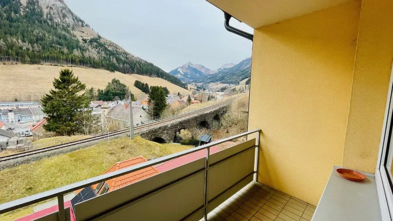 Balkon mit Fliesenboden und weitem Blick auf die umliegende Berglandschaft und das Tal.