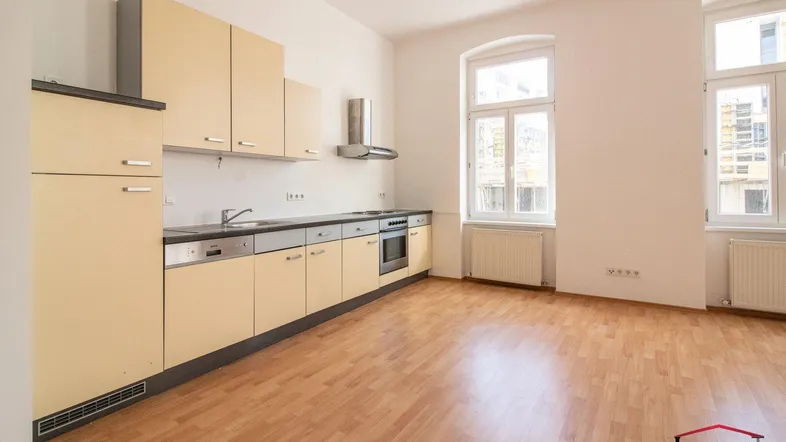 Helle Wohnküche mit Einbauküche, Parkettboden und großen Fenstern, die viel Tageslicht hereinlassen.