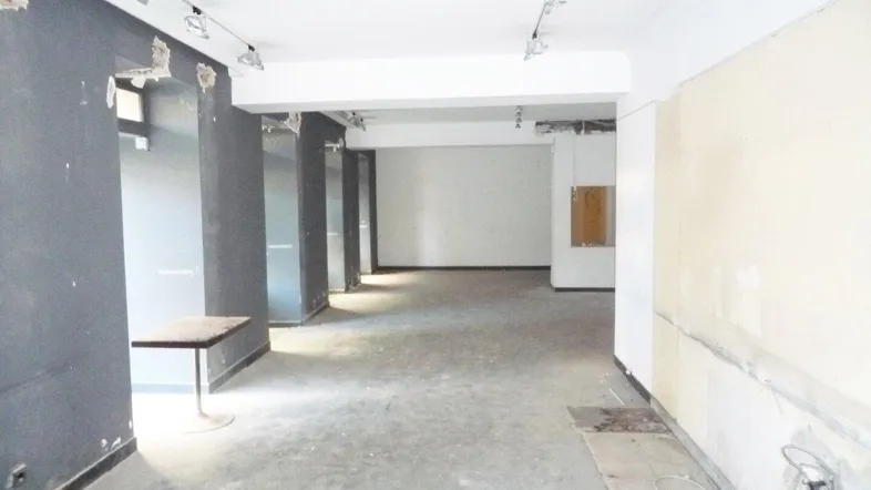 Großer, leerstehender Gewerberaum mit sichtbaren Abnutzungsspuren und deutlichem Renovierungsbedarf.