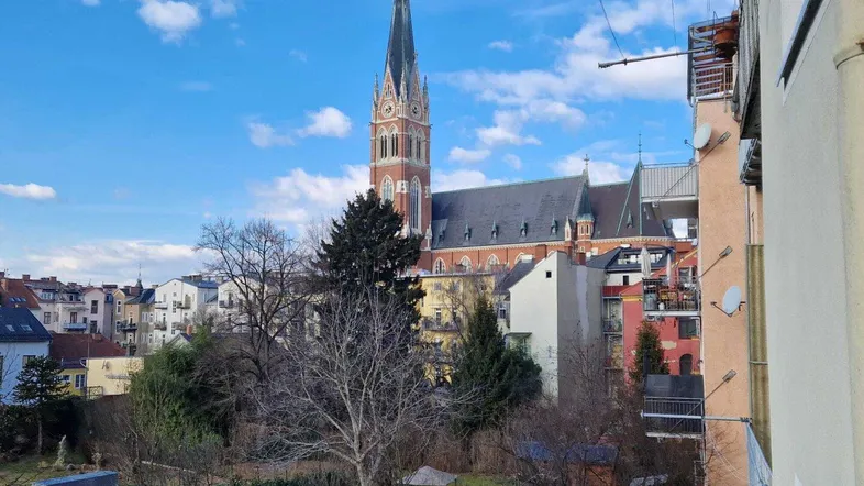 Blick auf eine historische Kirche und die umliegende Stadtlandschaft unter blauem Himmel.