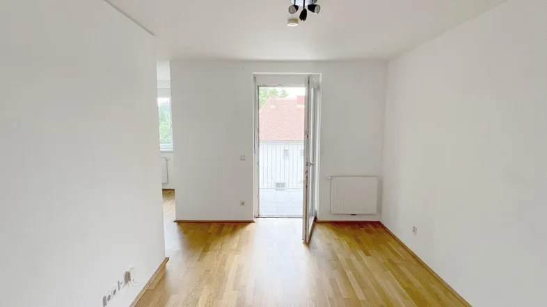 Heller Raum mit Parkettboden und Zugang zu einem Außenbereich, ideal als Wohnzimmer nutzbar.