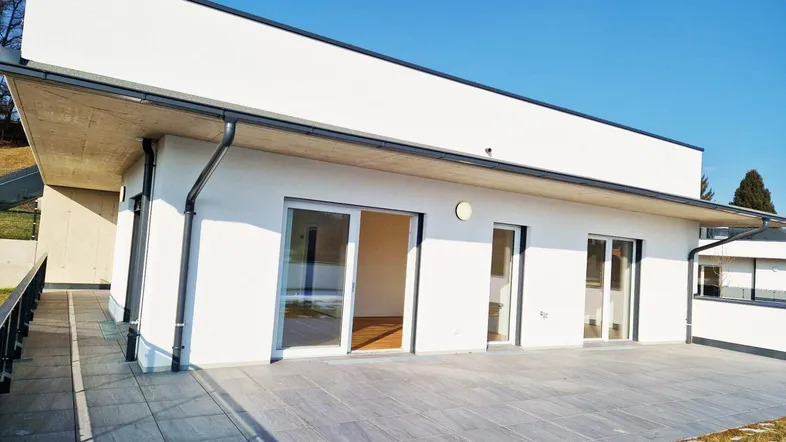 Moderne Neubauwohnung mit großer gefliester Terrasse und Zugang zu den Innenräumen.
