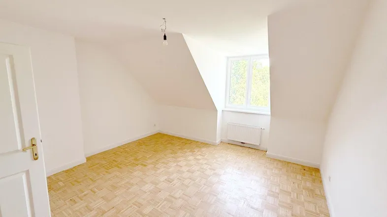 Helles Zimmer mit Dachschrägen und Parkettboden, ideal als Schlaf- oder Wohnbereich nutzbar.