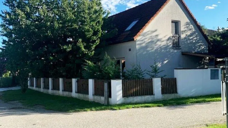 Hausfassade mit Satteldach und kleinem Balkon unter blauem Himmel.