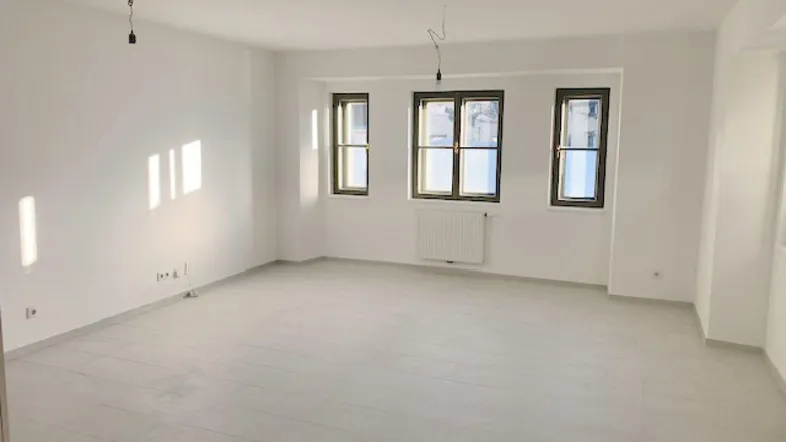 Helles, leeres Zimmer mit großen Fenstern und Fliesenboden, bereit zur individuellen Gestaltung.
