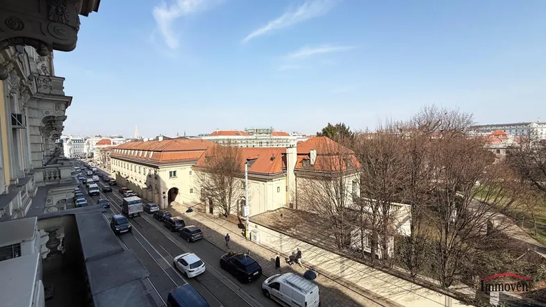 Blick von einem Balkon auf eine belebte Straße und historische Gebäude in der Stadt.