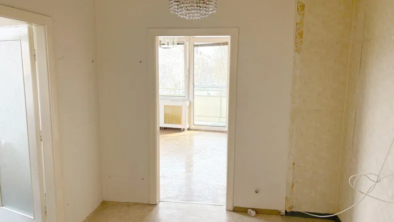 Leerer Innenraum mit Blick in ein weiteres Zimmer, bereit für Renovierungsarbeiten.