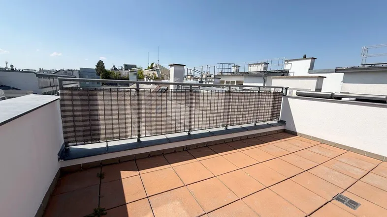 Geräumige Dachterrasse mit Fliesenboden und einem weiten Blick über die Dächer der Stadt.