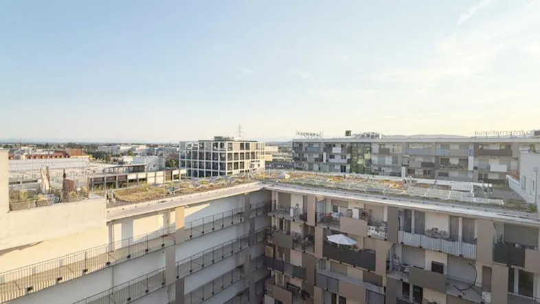 Weitläufiger Blick über die Dächer der Stadt und umliegende Wohngebäude bei klarem Himmel.