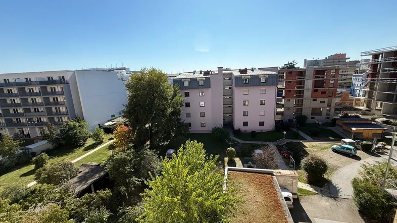Weitläufiger Blick über die umliegenden Gebäude und grüne Flächen unter blauem Himmel.