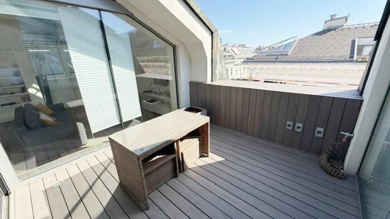 Moderne Dachterrasse mit Holzboden und Rattanmöbeln, ideal für entspannte Stunden im Freien.