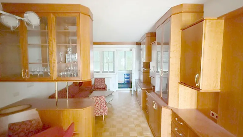 Geräumiges Wohnzimmer mit Holzmöbeln, Parkettboden und Zugang zu einem Wintergarten.