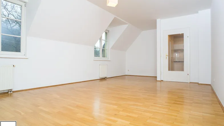 Helles Zimmer im Dachgeschoss mit Parkettboden und schrägen Wänden, ideal als Wohn- oder Schlafzimmer.
