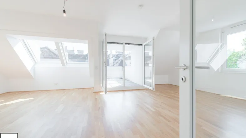 Helles, leeres Wohnzimmer mit Holzboden, Dachfenstern und Zugang zu einem Außenbereich.