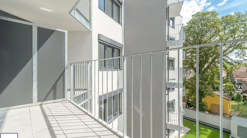 Heller Balkon mit Metallgeländer und Blick auf die umliegenden Gebäude und Grünflächen.