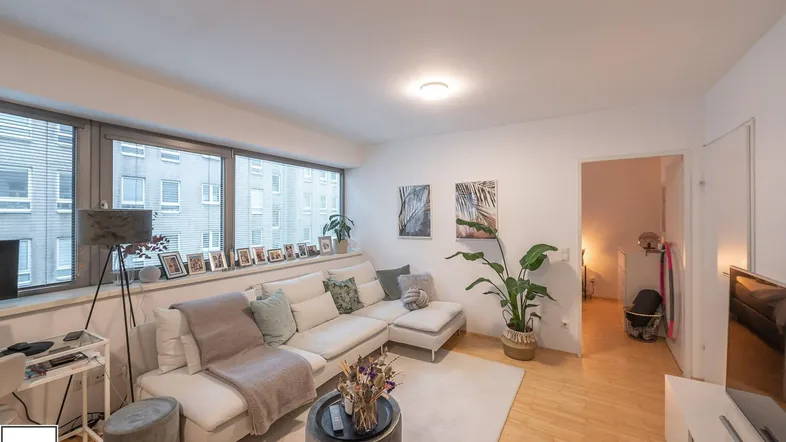 Helles Wohnzimmer mit großzügiger Fensterfront, modernem Sofa und Holzboden.