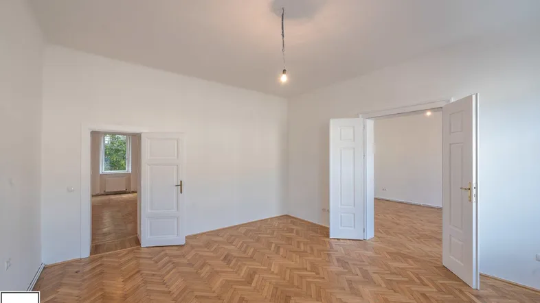 Helles Zimmer mit Fischgrätparkettboden und weißen Flügeltüren, die zu weiteren Räumen führen.