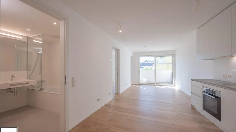 Helles, offenes Wohnzimmer mit integrierter Küche und Zugang zu einem modernen Badezimmer.