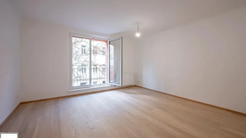 Helles Zimmer mit Holzboden und Zugang zu einem französischen Balkon, ideal als Wohn- oder Schlafzimmer.