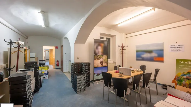 Großer Büroraum mit gewölbter Decke, Teppichboden und mehreren Arbeitsbereichen, ideal für ein Team.
