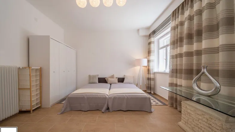 Helles Schlafzimmer mit zwei Einzelbetten, Fliesenboden und großem Fenster.
