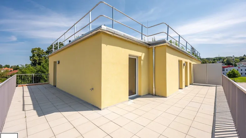 Große Dachterrasse mit Fliesenboden und Metallgeländer, ideal für Entspannung im Freien unter blauem Himmel.