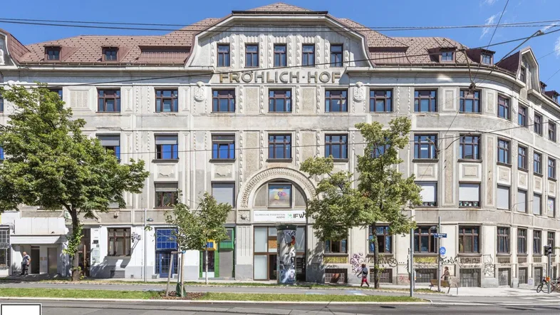 Historisches Gebäude mit markanter Fassade und dem Schriftzug "FRÖHLICH-HOF" an einem sonnigen Tag.