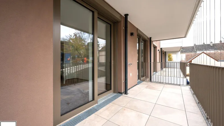 Langer, gefliester Balkon mit moderner Brüstung und Blick auf die Umgebung.