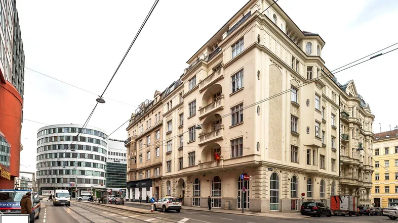 Klassisches Eckgebäude mit historischer Architektur und Blick auf die belebte Stadtstraße.