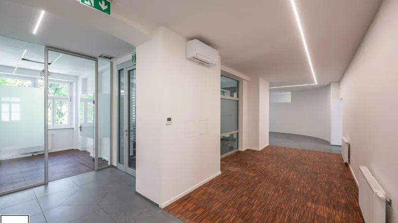 Moderner Bürobereich mit Holzboden und Fliesen, ausgestattet mit Klimaanlage und Glaswänden für eine offene Atmosphäre.