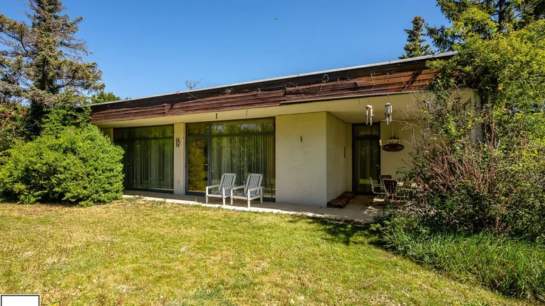 Einfamilienhaus mit großem Garten und kleiner Terrasse, umgeben von viel Grün.