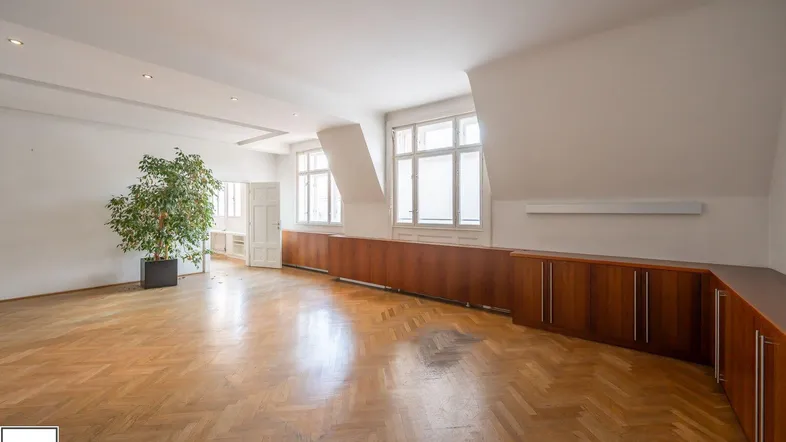 Geräumiges Büro mit Fischgrätparkett, großen Fenstern und integrierten Holzschränken entlang der Wand.