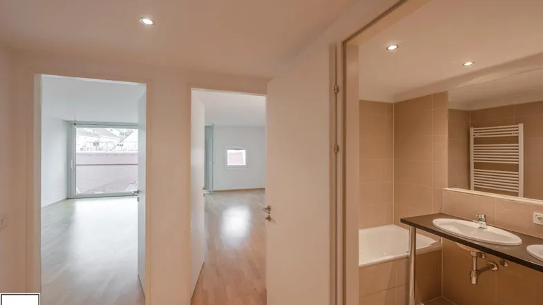 Heller Flur mit Holzfußboden, der zu einem modernen Badezimmer und einem weiteren Zimmer führt.